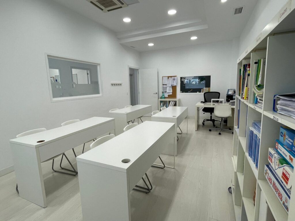 Aula de eduCa con mesas blancas y material para actividades educativas
