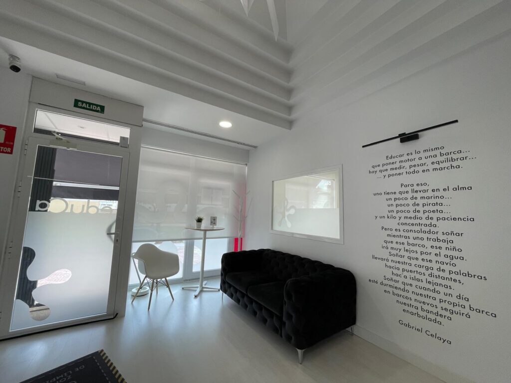 Zona de espera de eduCa con sofá oscuro y puerta de entrada